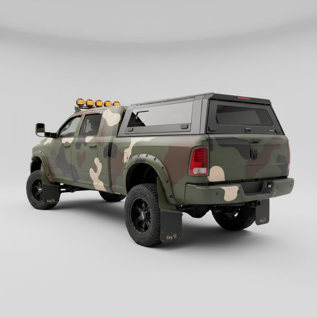 A lifted Ram pickup truck with a custom camouflage paint job, featuring a hard cap canopy, black roof racks, and off-road tires, parked in a residential driveway.